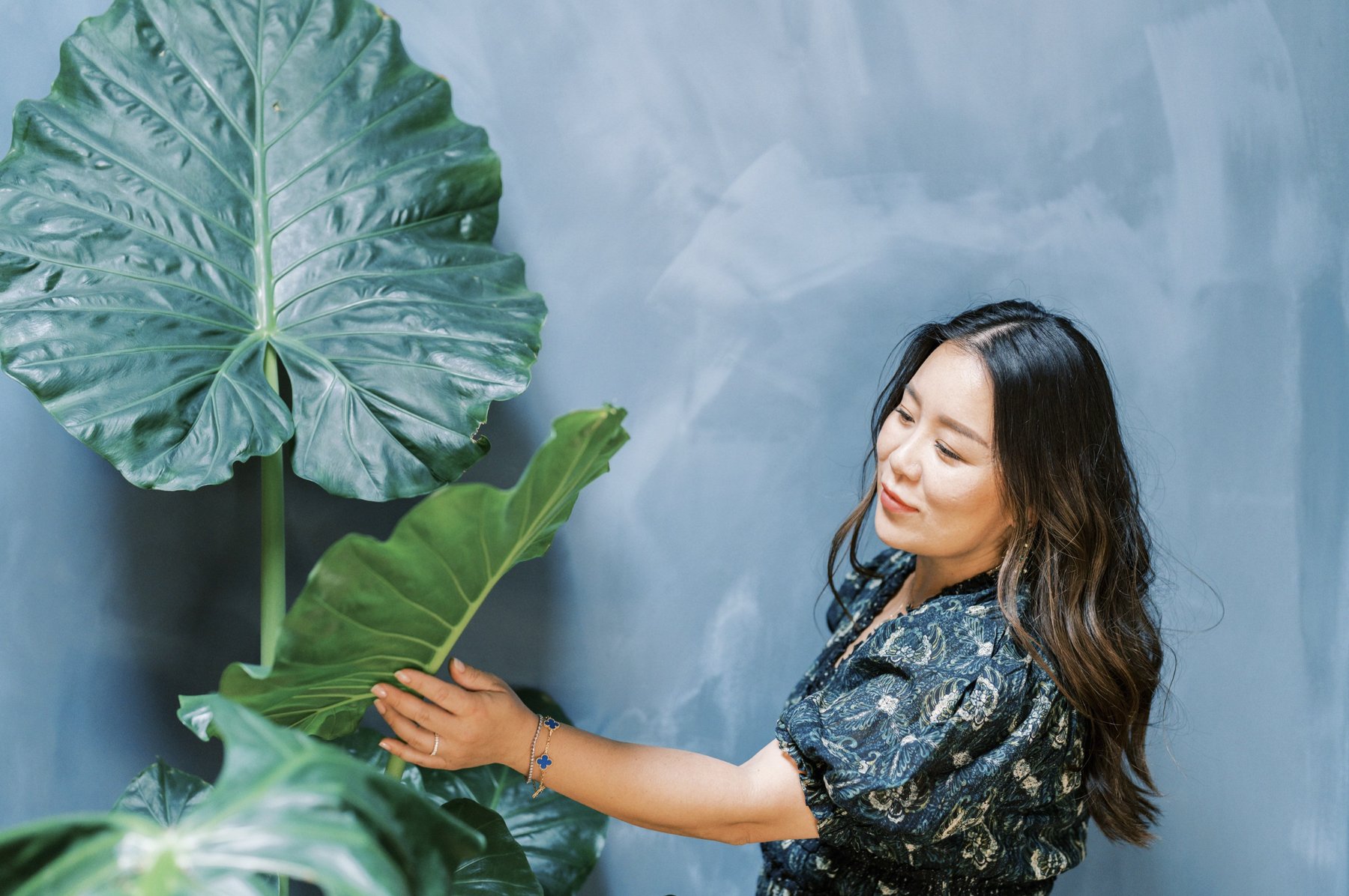 Founder of Chloe + Mint holding a large tropical leaf